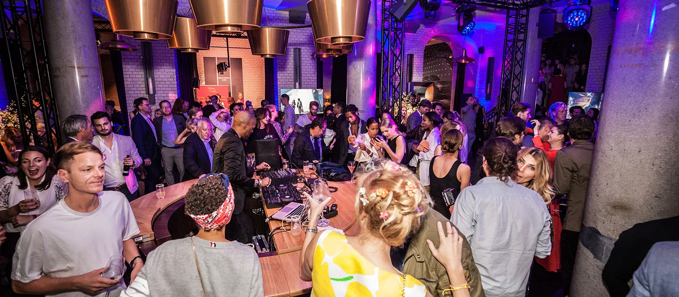 Gäste feiern im violett beleuchteten Gewölbe bei 20 Jahre GQ in Berlin