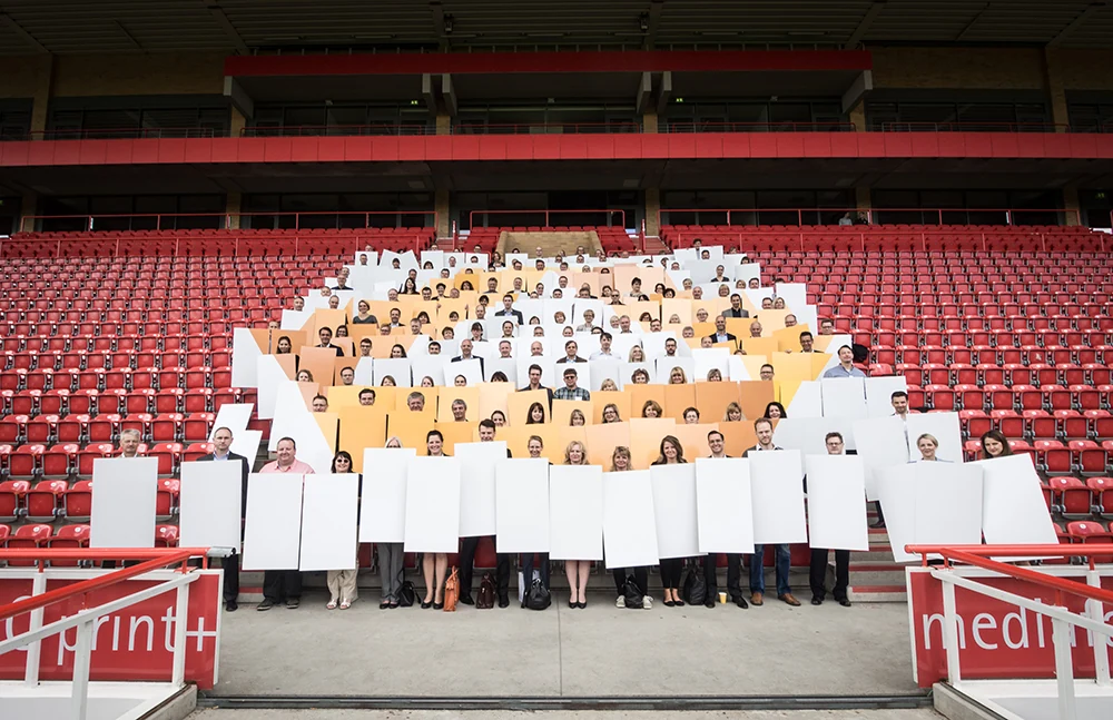 Teamfoto der Commerzbank Region Ost auf der Stadiontribüne mit weißen Tafeln