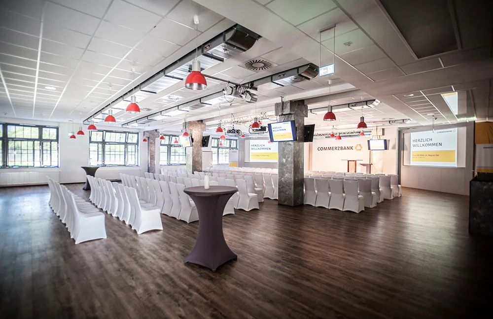 Veranstaltungshalle mit Commerzbank-Stelen, Stehtischen und Screens