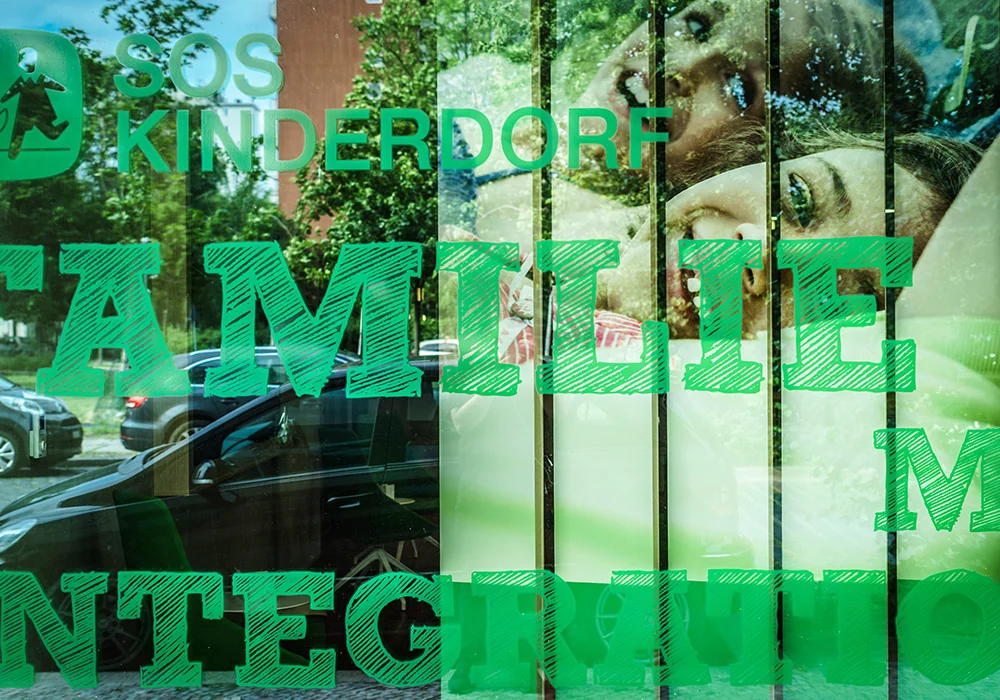 Schriftzug FAMILIE und INTEGRATION auf der Glasfassade der Botschaft für Kinder