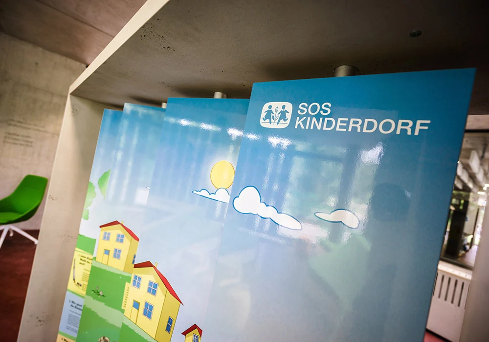 Aufsteller mit SOS-Kinderdorf Logo und Illustration in der Botschaft für Kinder